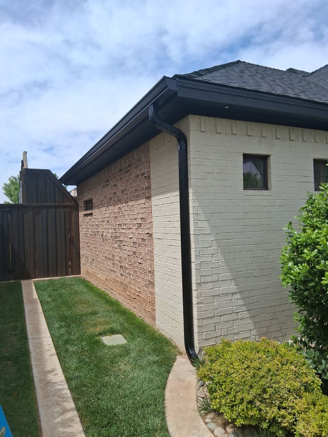 Black seamless gutters and downspout on a two-tone brick Lubbock home