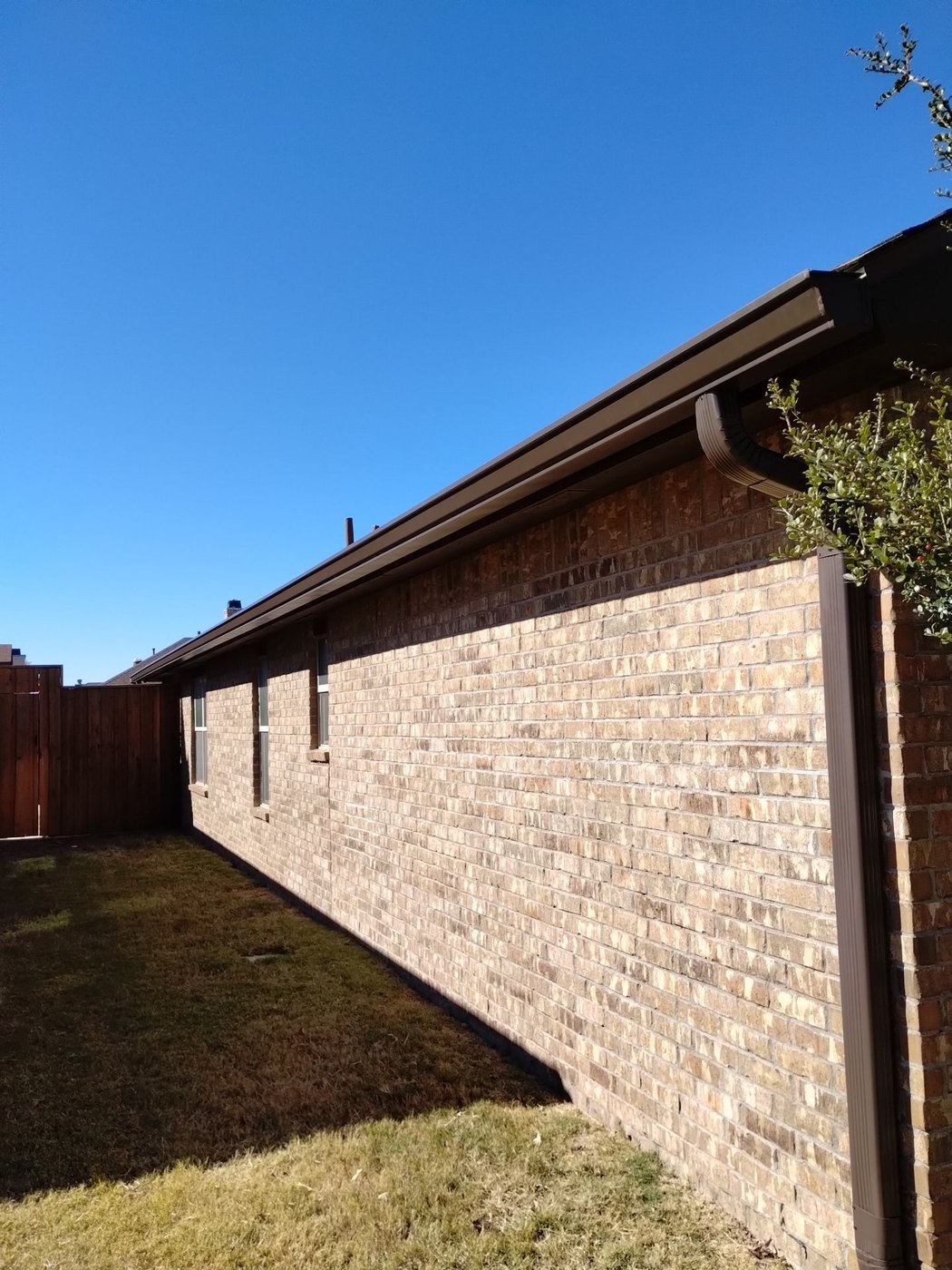A long continuous brown seamless gutter run on a Lubbock brick home