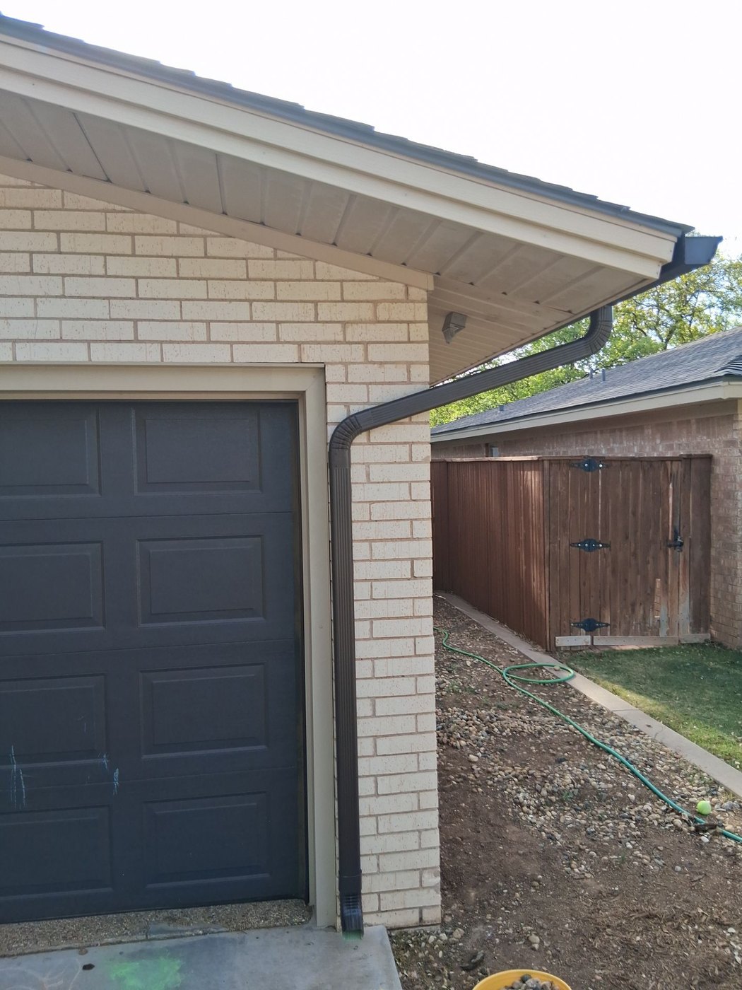 Bronze seamless downspout with a clean elbow on a Lubbock brick home