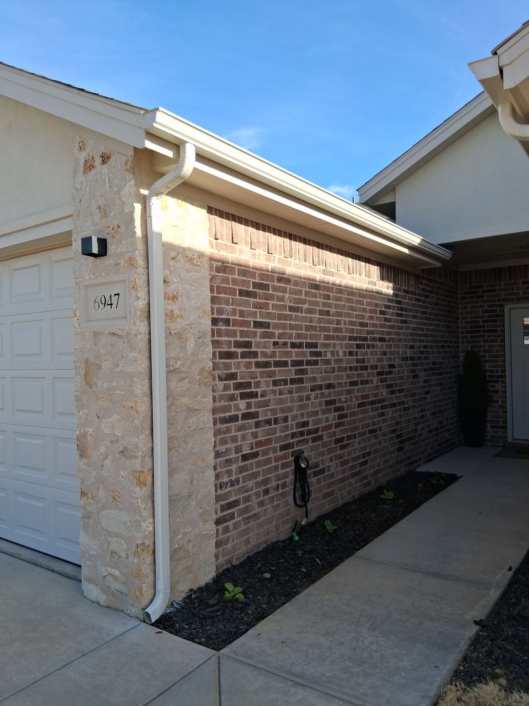 White seamless gutters on a stone-and-brick Lubbock home